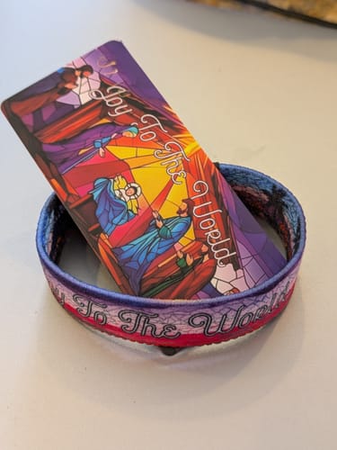 Reviewer's Joy To The World Bible Verse Bracelet displayed with its matching card showing a stained-glass nativity scene.