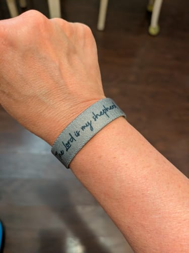 Customer wearing the grey Bible Verse Bracelet with 'The Lord is my shepherd' script on their wrist.