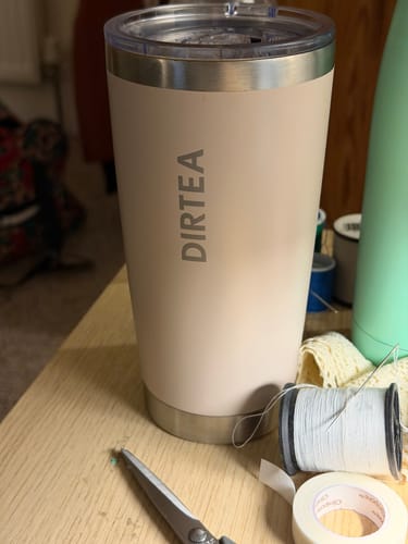 Reviewer's beige DIRTEA tumbler with their matcha on a desk with craft supplies.