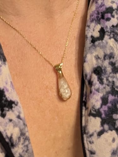 Reviewer's close-up of the Rose Drop Pendant with infused ash, worn on a gold chain.