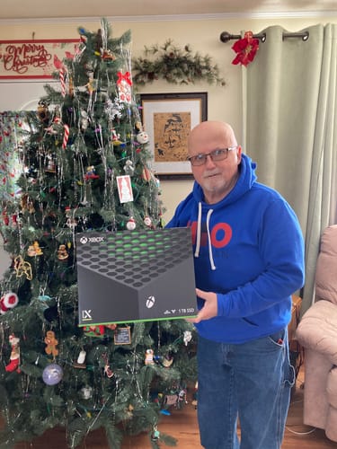 Reviewer in a blue hoodie holding the box for an Xbox they won as a prize.