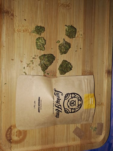 Ein Kunde zeigt die grünen Blüten des Lemon Gelato Ökopacks neben der Verpackung auf einem Holzbrett.