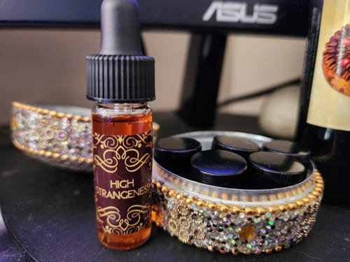 Customer's High Strangeness dram dropper bottle with amber liquid on a desk.
