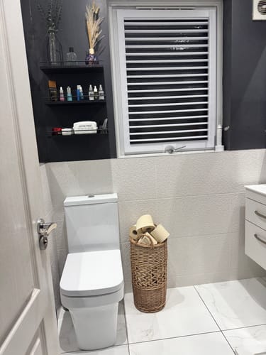 Reviewer's unbleached bamboo toilet paper rolls completely filling a tall wicker basket in a bathroom.