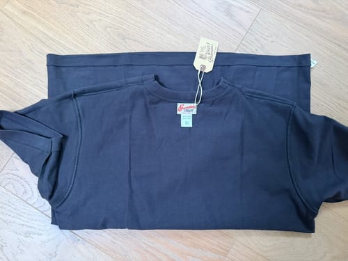 Customer's vintage black Loopwheel Tubular Athletic T-Shirt neatly folded on a wooden surface, with tag still attached.