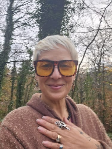 Reviewer smiling outdoors while wearing the funky, square driving glasses with yellow lenses.