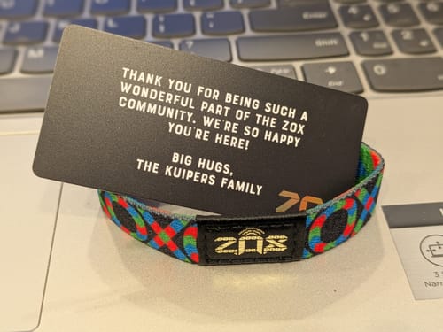 Customer's F&F Spectra Interactive Bracelet with a colorful XOXO pattern, displayed with a black thank you card.