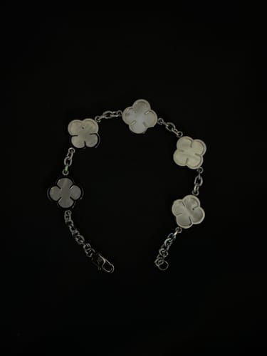 Reseñador muestra la Pulsera White Clover con sus tréboles blancos sobre un fondo negro.