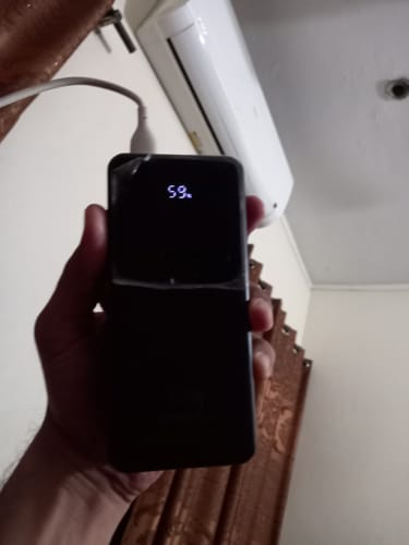 Customer holding the black 40,000mAh Powerbank, which shows 59% on its digital display while plugged in.