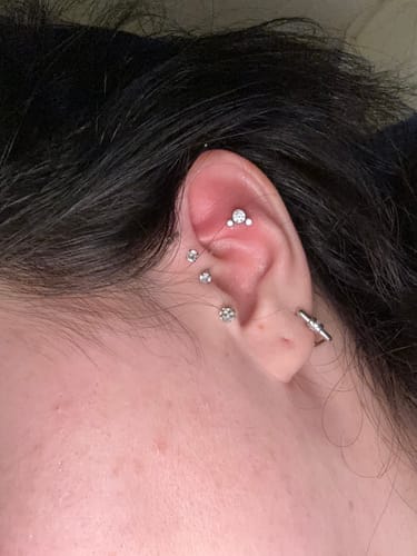 Ein Kunde trägt das Little Mouse Piercing im oberen Knorpel des Ohres, kombiniert mit anderen Steckern.