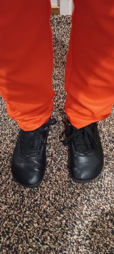 Asiakkaan jalassa mustat Vaistoa Suisto -paljasjalkavaelluskengät sisätiloissa matolla.