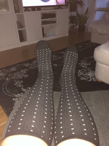Recensent som bär sina svarta, prickiga Diasocks stödstrumpor i ett vardagsrum.