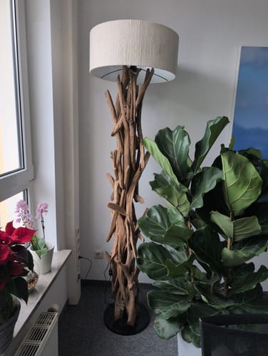 Kundenfoto der rustikalen Stehlampe BLUMA aus Teakholz mit beigem Lampenschirm in einem Wohnraum.