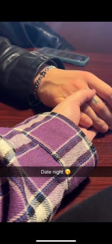 Customer wearing the Anarchy Cuban Bracelet on their wrist while holding another person's hand at a table.