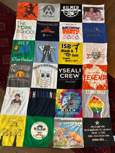 Customer's colorful Premium T-Shirt Quilt laid flat, showing a variety of t-shirt squares with unique graphics and text.
