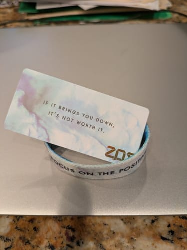 Customer's Focus on the Positive bracelet with an inspirational card resting on a laptop.