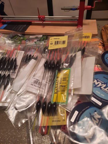 Beoordelaar toont meerdere verpakkingen van de Preston Kerry dobbers op een tafel vol visgerei.