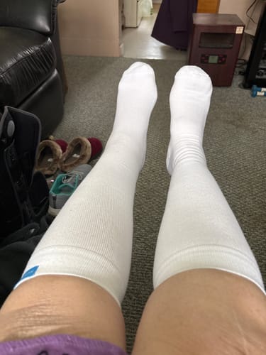 Reviewer's point of view wearing the white Performance Eucalyptus Compression Socks up to their knees.