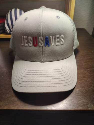 Reviewer's gray patch hat with 'JESUSAVES' embroidered on the front. The letters 'U' and 'A' are styled in red and blue.