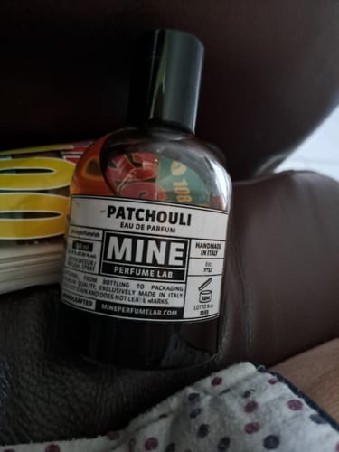 Recensore mostra in primo piano la sua boccetta di profumo Patchouli.