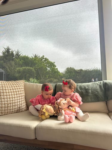 Customer's two babies sitting on a couch playing with their Personalized Sunny Girl & Her Pet dolls.