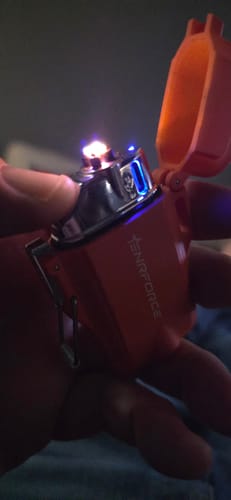 Close-up of a reviewer holding the orange Arc Lighter with its electric arc ignited in their hand.
