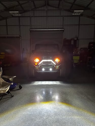 Customer's Goliath Grille installed on a Jeep, with its bright LED DRL and turn signals illuminating a dark garage.
