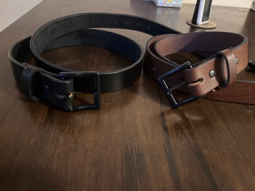 Customer's black and brown 'The Everyday' work belts coiled on a wooden table.
