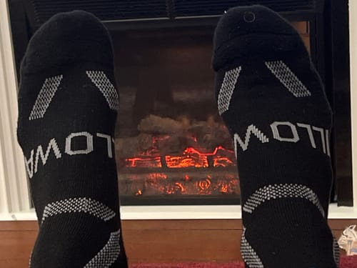 Customer showing the black 'Hollow' socks mentioned in the review for comparison in front of a fireplace.