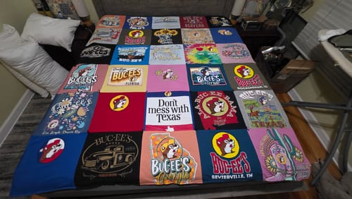 Customer's custom Premium T Shirt Quilt made from many colorful Buc-ee's shirts, spread across a bed.