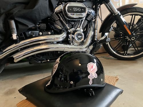 Customer's gloss black Polo Helmet with stickers, shown in front of a motorcycle.