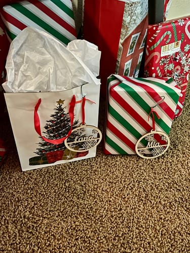 Customer's personalized Christmas ornaments used as lovely gift tags on a gift bag and a wrapped present.