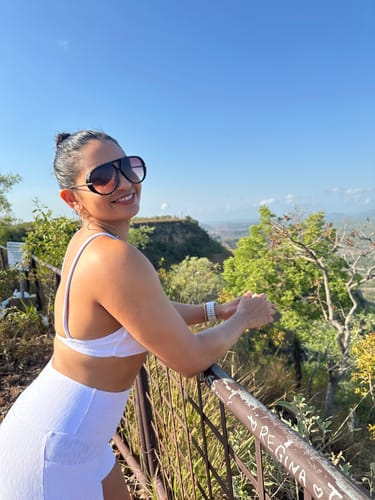 Cliente sorrindo em uma área externa, usando os grandes Óculos Veneza com lentes degradê.