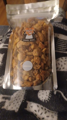 Customer's full, clear resealable bag of Original Flavour Pork Scratchings sitting on a patterned blanket.