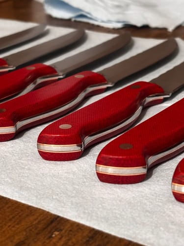Customer's set of knives with smooth, red handles contoured using the sanding belts.