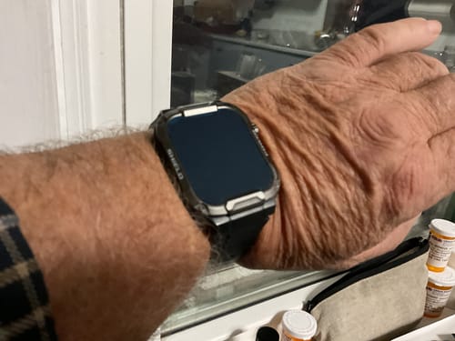Reviewer's wrist showing a smartwatch in a rugged protective case.