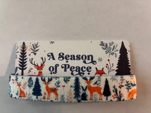 Customer's 'A Season of Peace' bracelet with a woodland animal pattern, displayed on its packaging card.