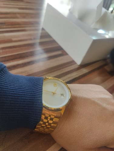 Customer showing the elegant gold-colored Onyx watch on their wrist, with the box in the background.