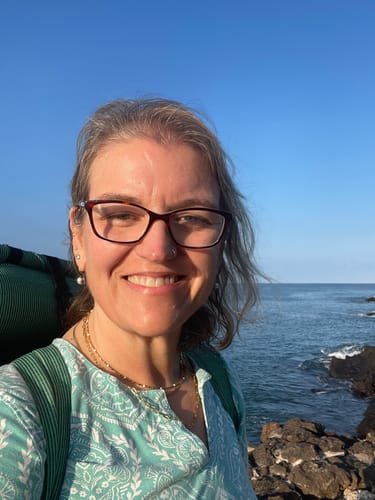 Reviewer smiling outdoors, wearing the layered Maui Paperclip Necklace by the ocean.