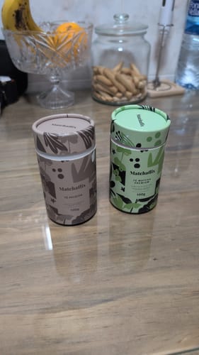 Cliente muestra su envase de Hojicha Premium en una mesa de cocina, junto a otro té.