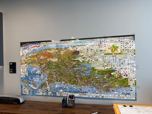 Reviewer's large World's Greatest Search & Discover poster mounted on an office wall over a desk.