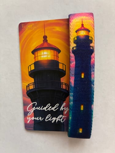 Reviewer's Guided By Your Light Bracelet next to its matching card, showing a colorful lighthouse against a sunset.