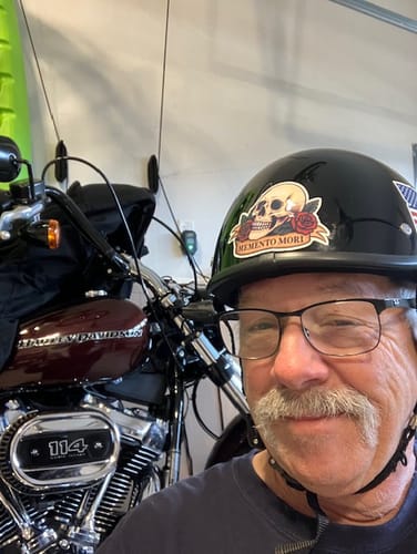 Reviewer smiling while wearing the gloss black Polo Helmet with stickers in a garage.