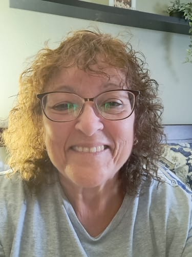 A smiling reviewer shows off her curly, shoulder-length hair after using the Fresh Roots Conditioner.