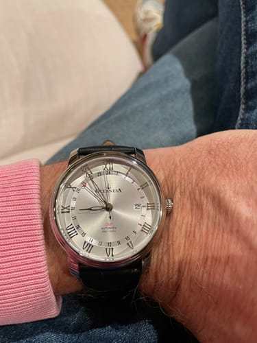 Customer's Oceaneva OceanTrek GMT watch with a silver dial and black leather strap on their wrist.