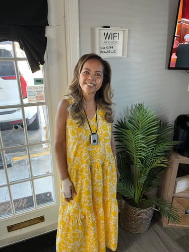 Customer smiling in a yellow floral dress, feeling healthy after taking Emma supplements.