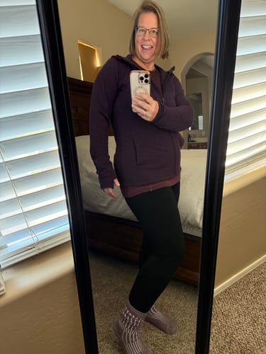Reviewer in a mirror selfie wearing the Hannah Long Sleeve Top in Chocolate Fig layered under a hoodie.