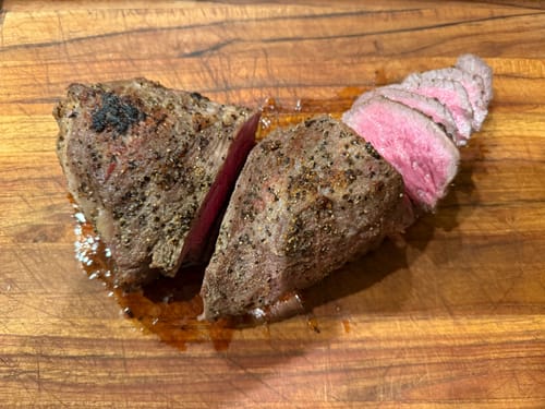 Customer's cooked USDA Choice Tri-tip on a cutting board, sliced to show a pink medium-rare center.