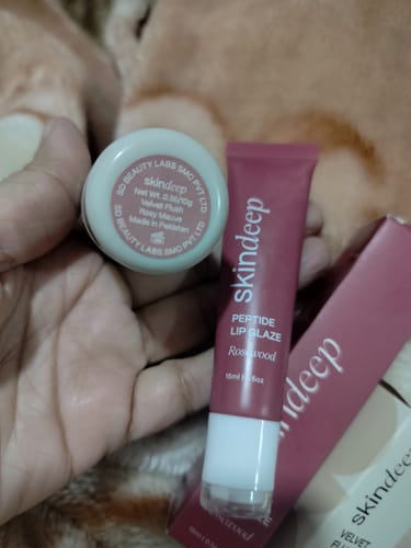 Customer holding the Rosewood Peptide Lip Glaze tube and the Rosy Mauve Velvet Flush pot.