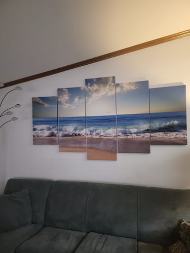 Customer's five-panel Relaxing Waves canvas art displayed over a dark sectional sofa.